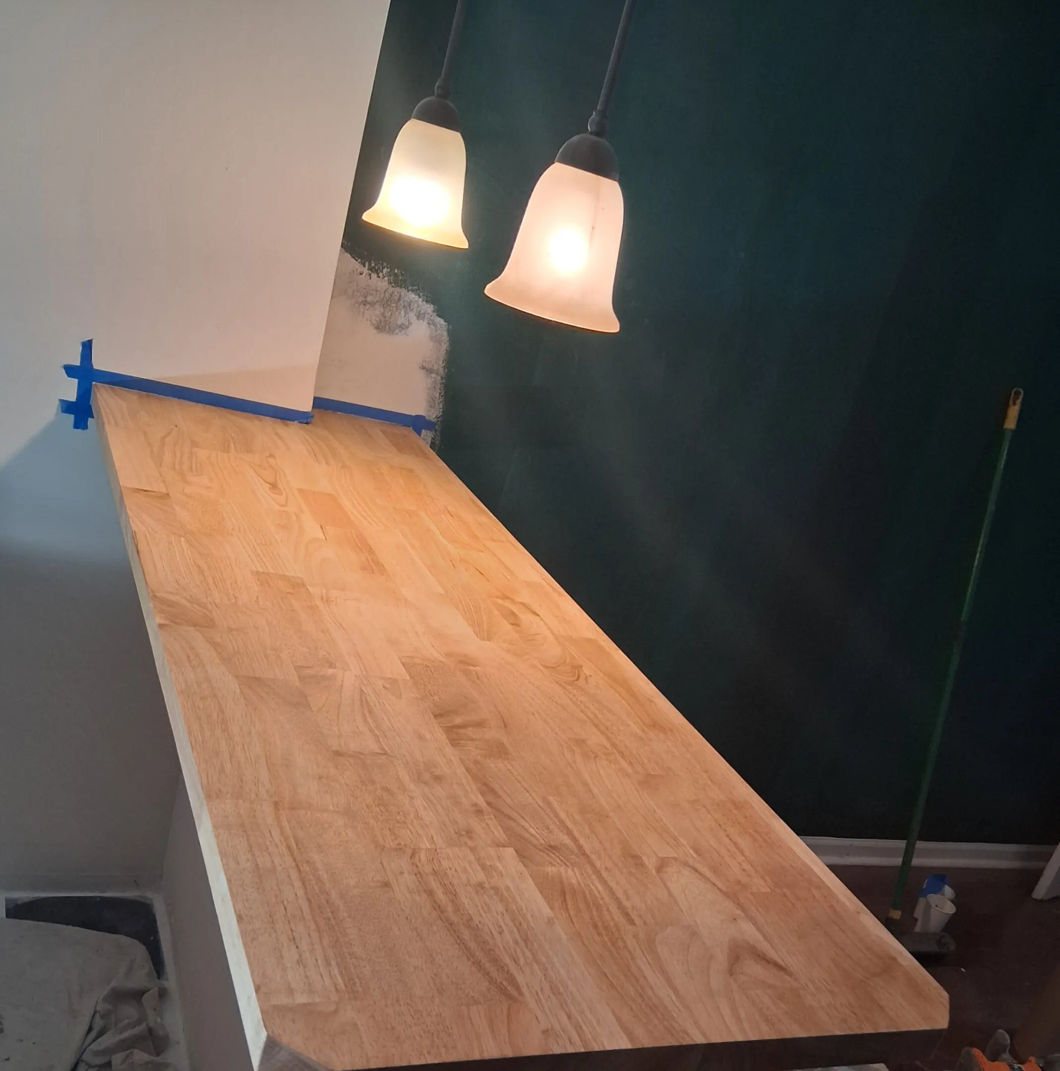 A wooden countertop with two pendant lights above it in a dimly lit room.