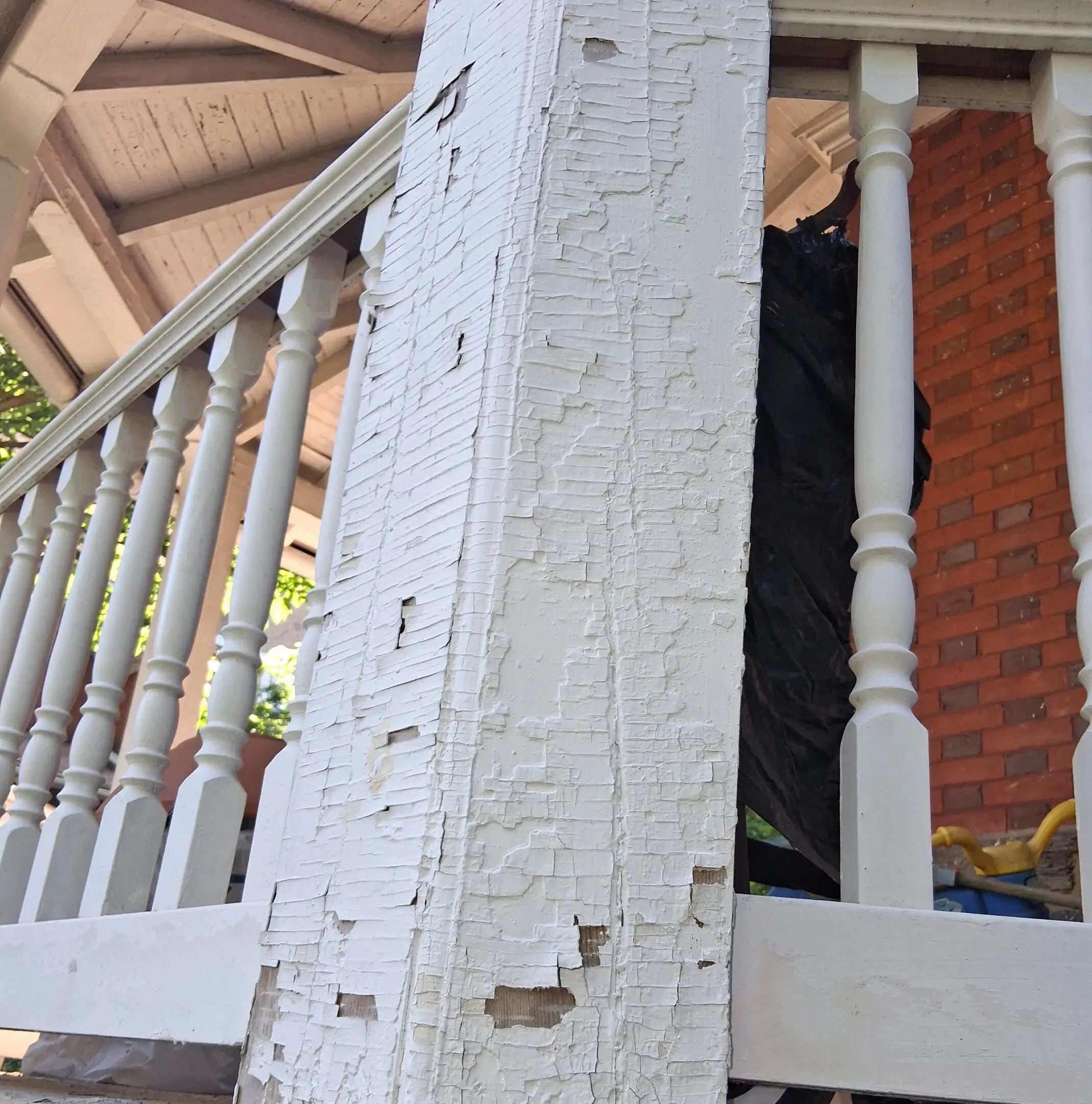 Close-up of worn and chipped white porch railing with visible paint damage.