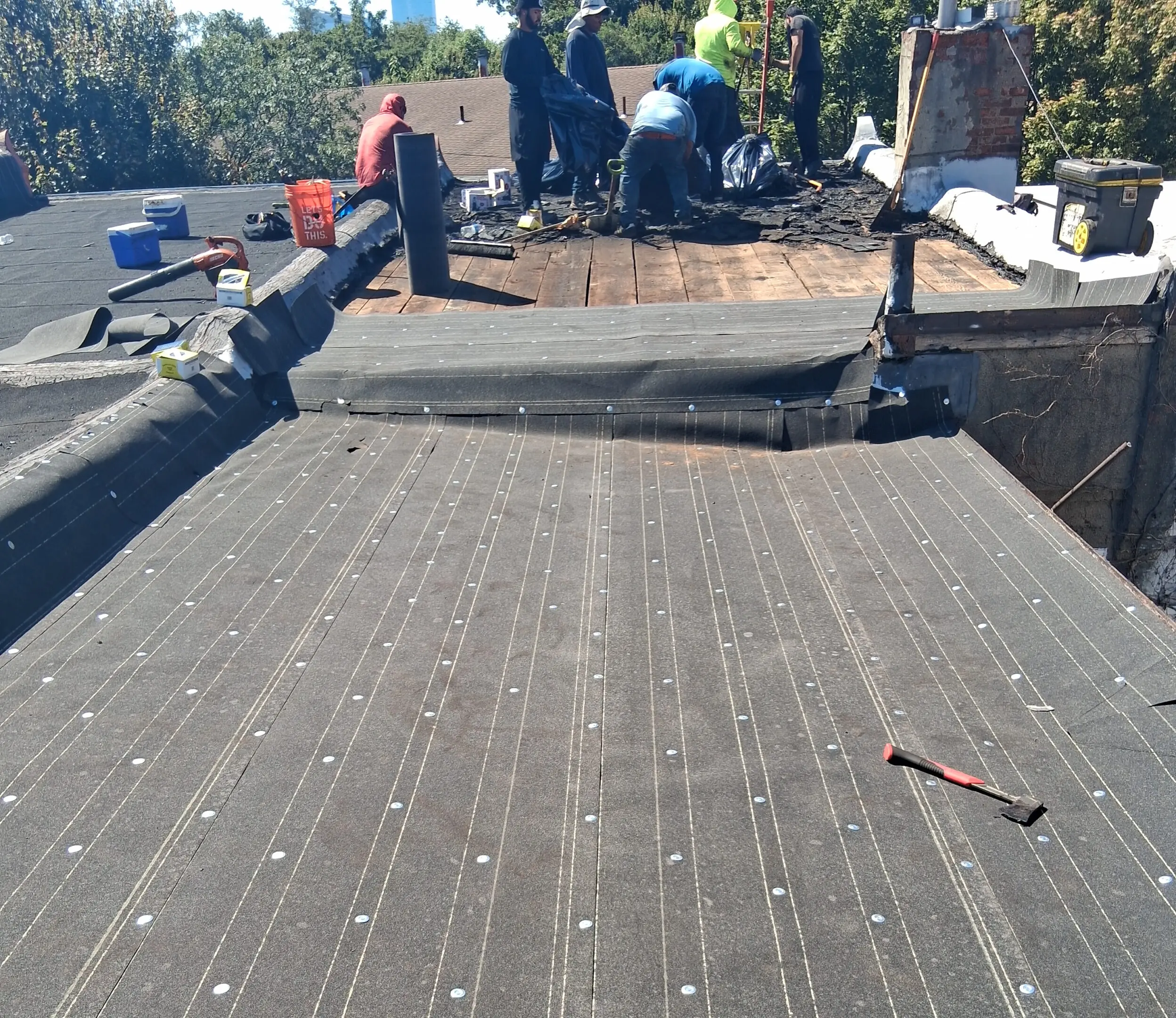 Workers installing waterproofing membrane on a flat roof.