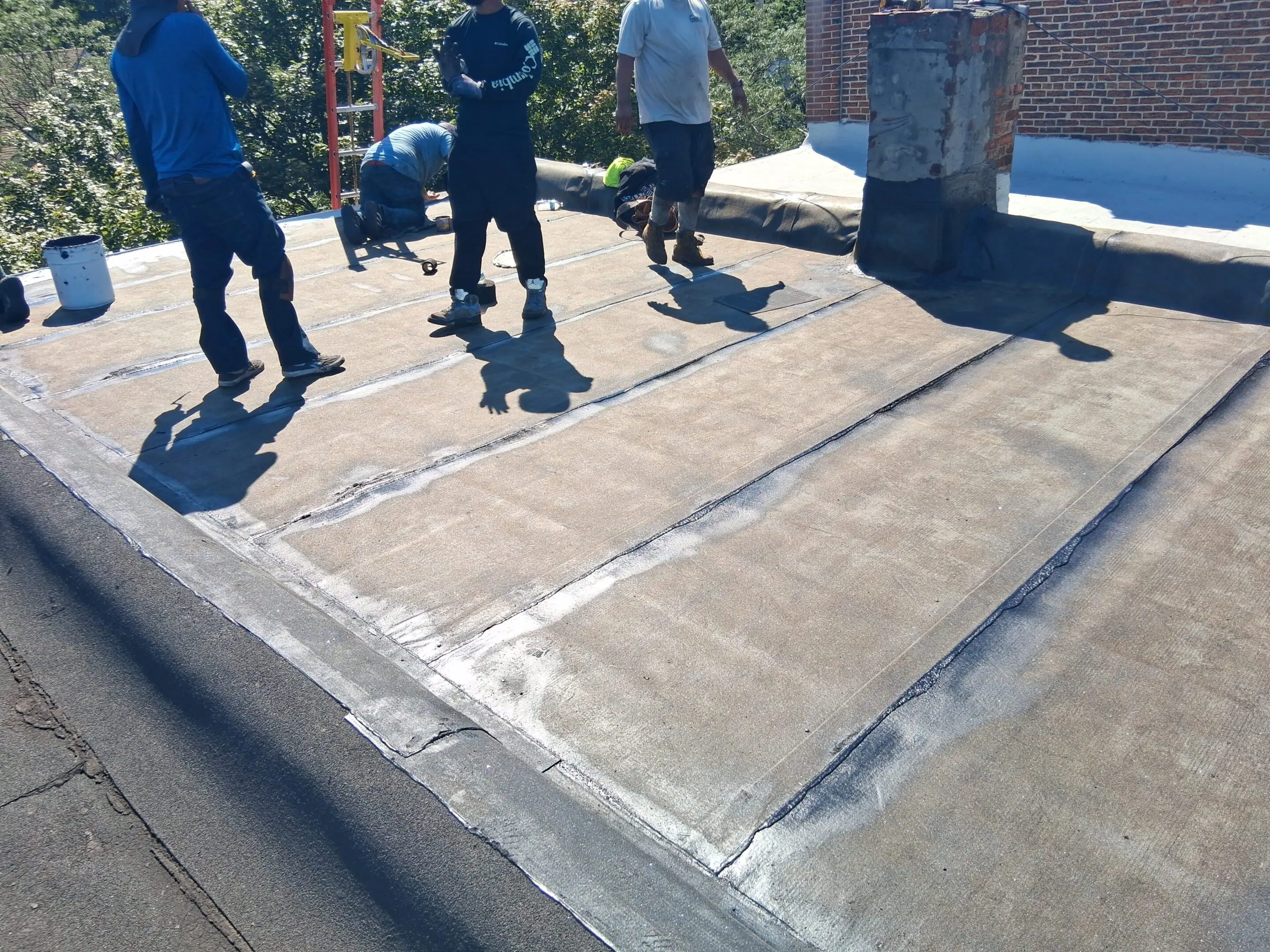 Workers inspecting a flat rooftop with new sealing.