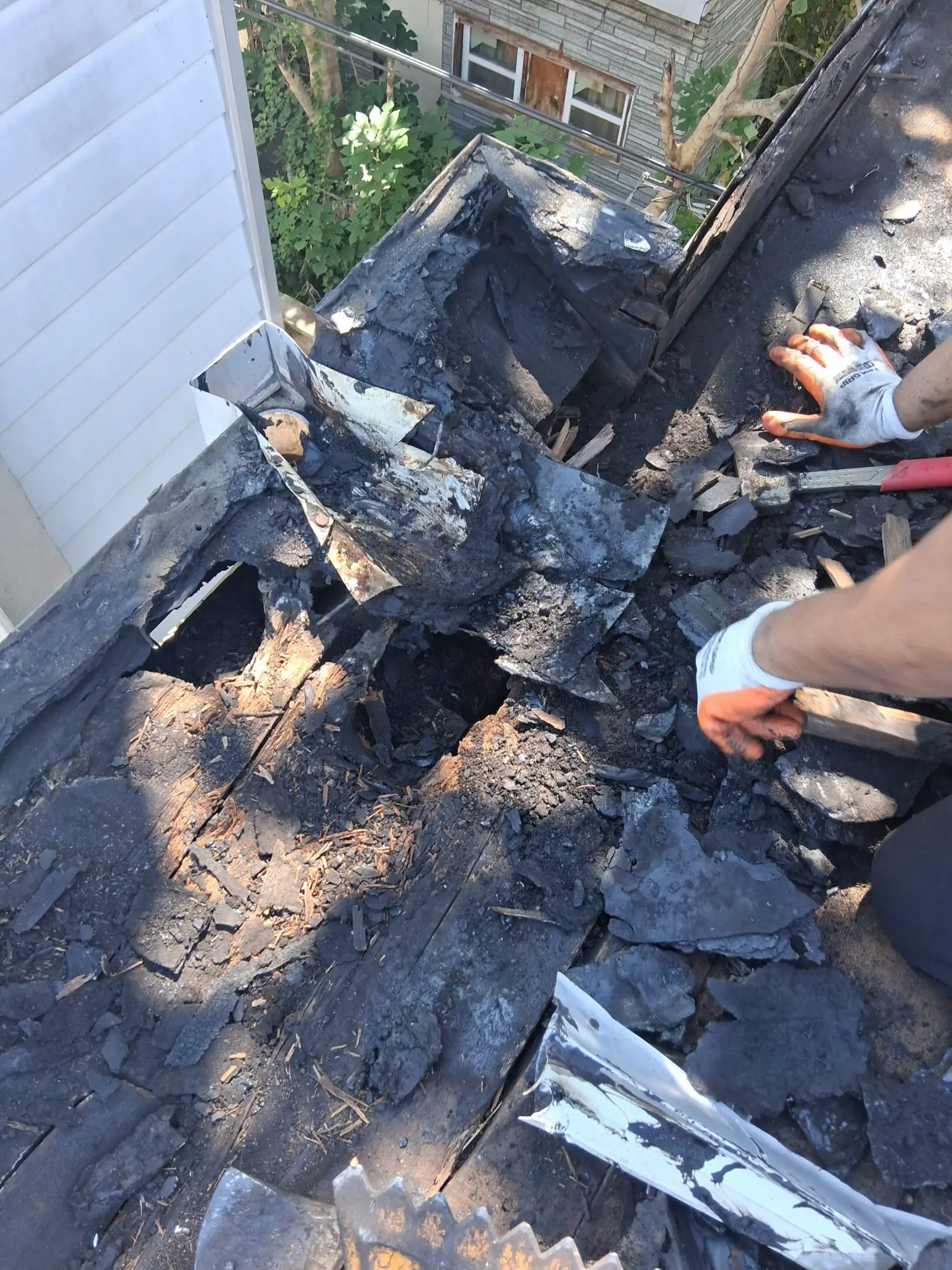 People repairing a severely damaged roof with burnt materials.