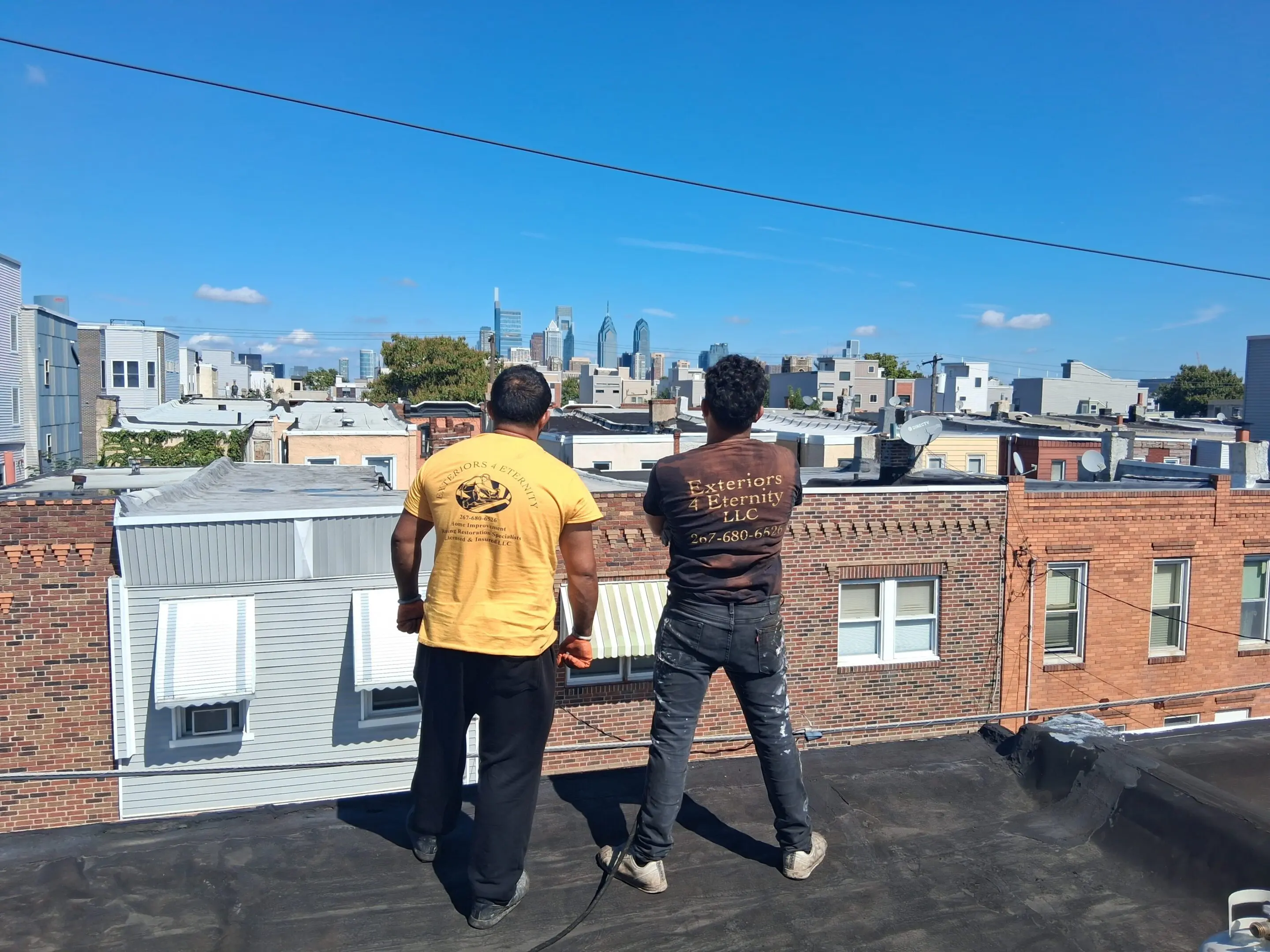 Two people and a dog stand on a rooftop overlooking a city skyline.