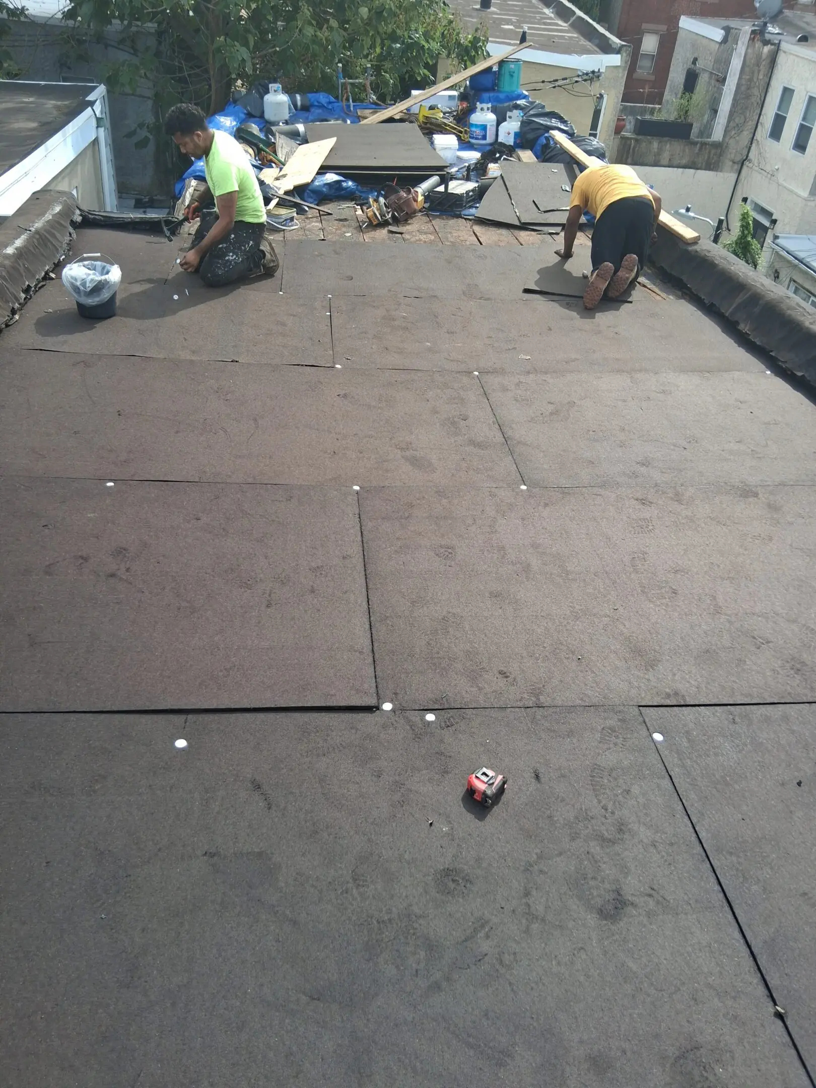 Workers installing roofing material on a flat roof.