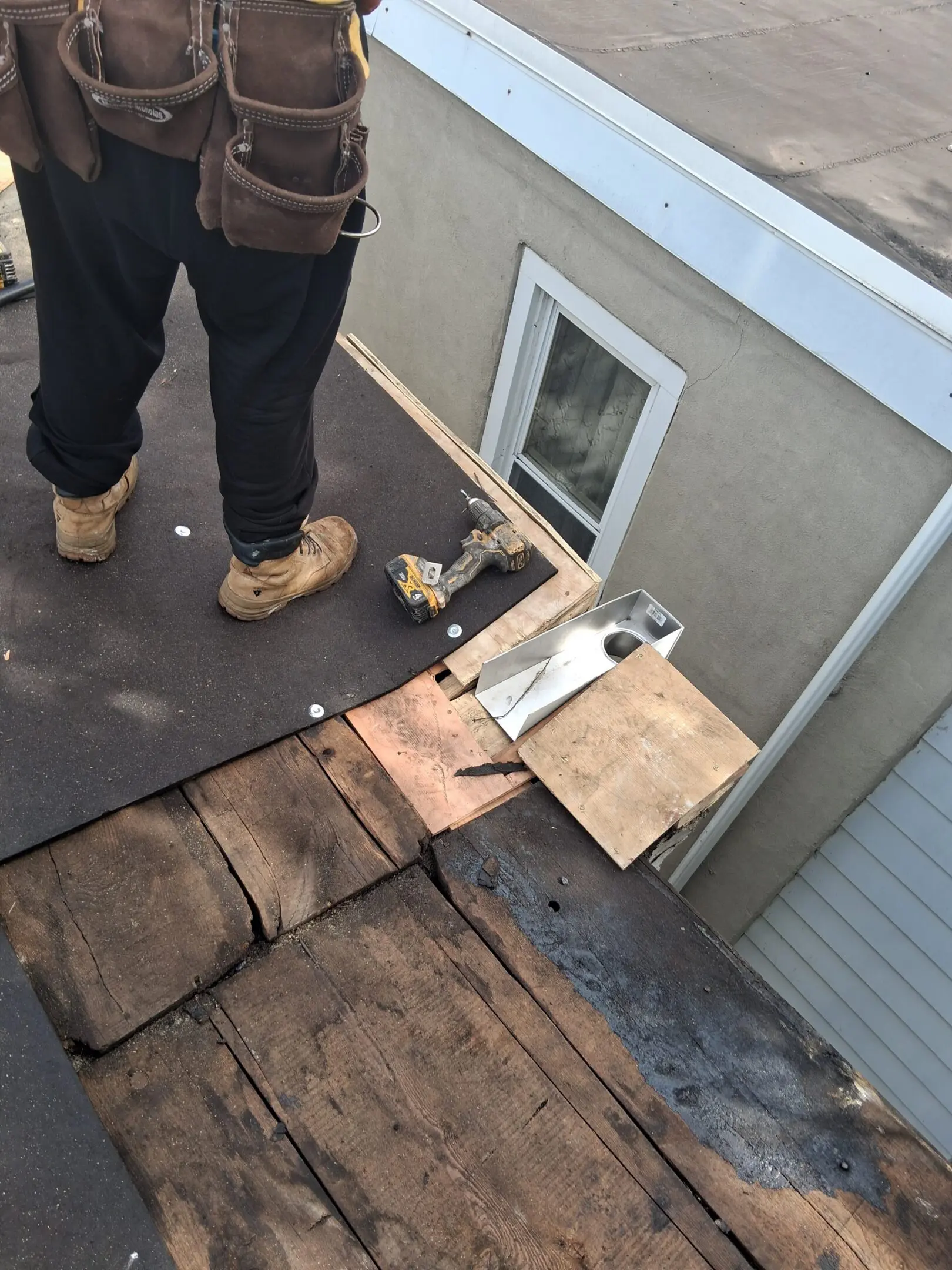 A person working on a roof with tools and materials scattered around.