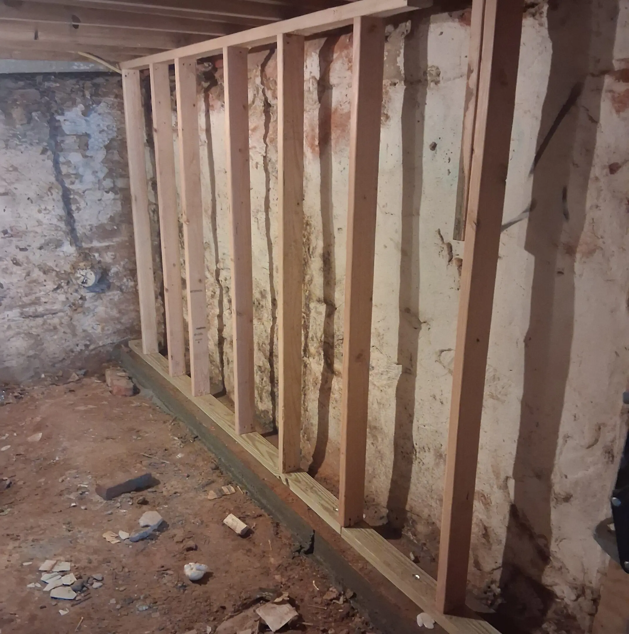 Newly framed wooden wall in a basement under renovation.