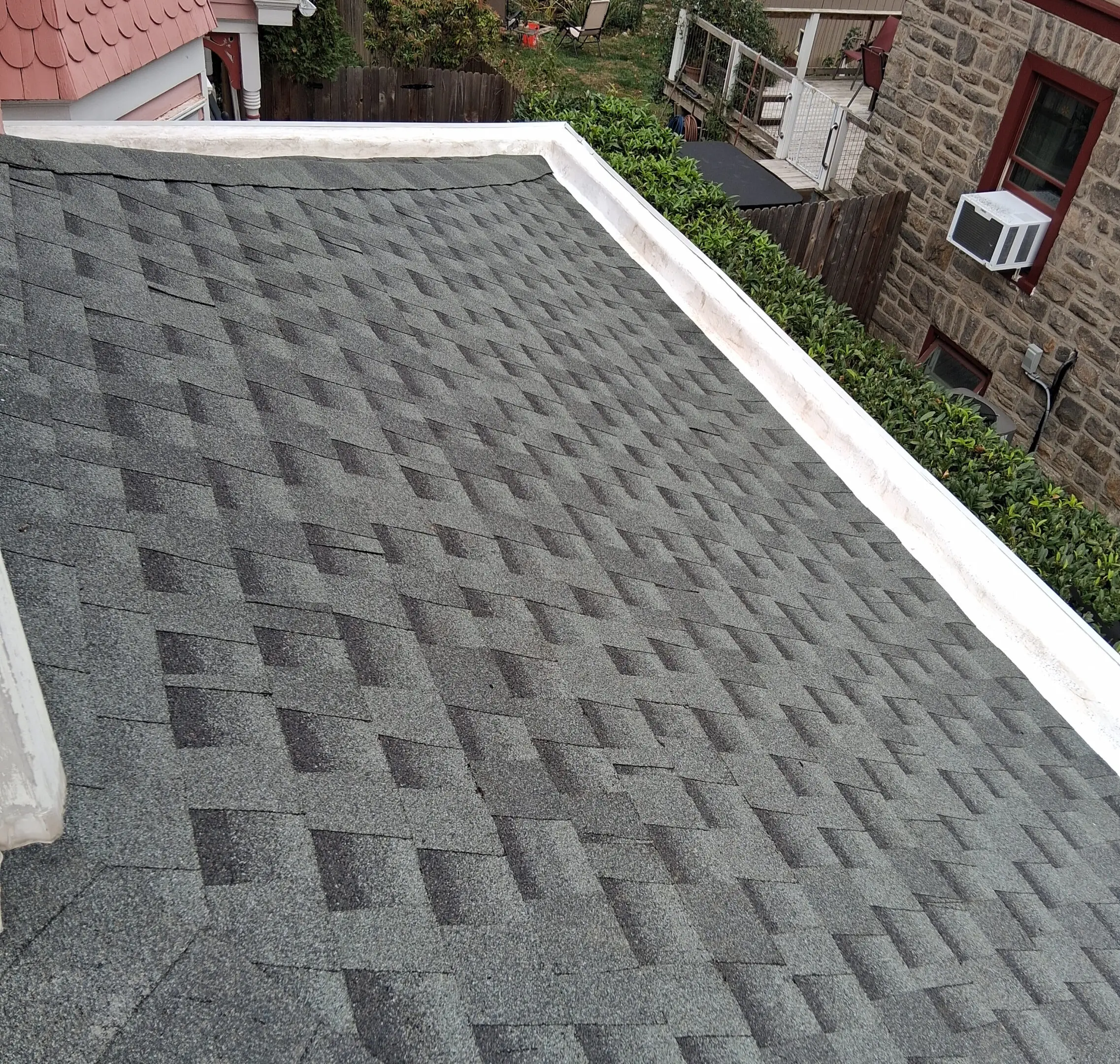 A newly shingled roof with a neat pattern in an urban setting.