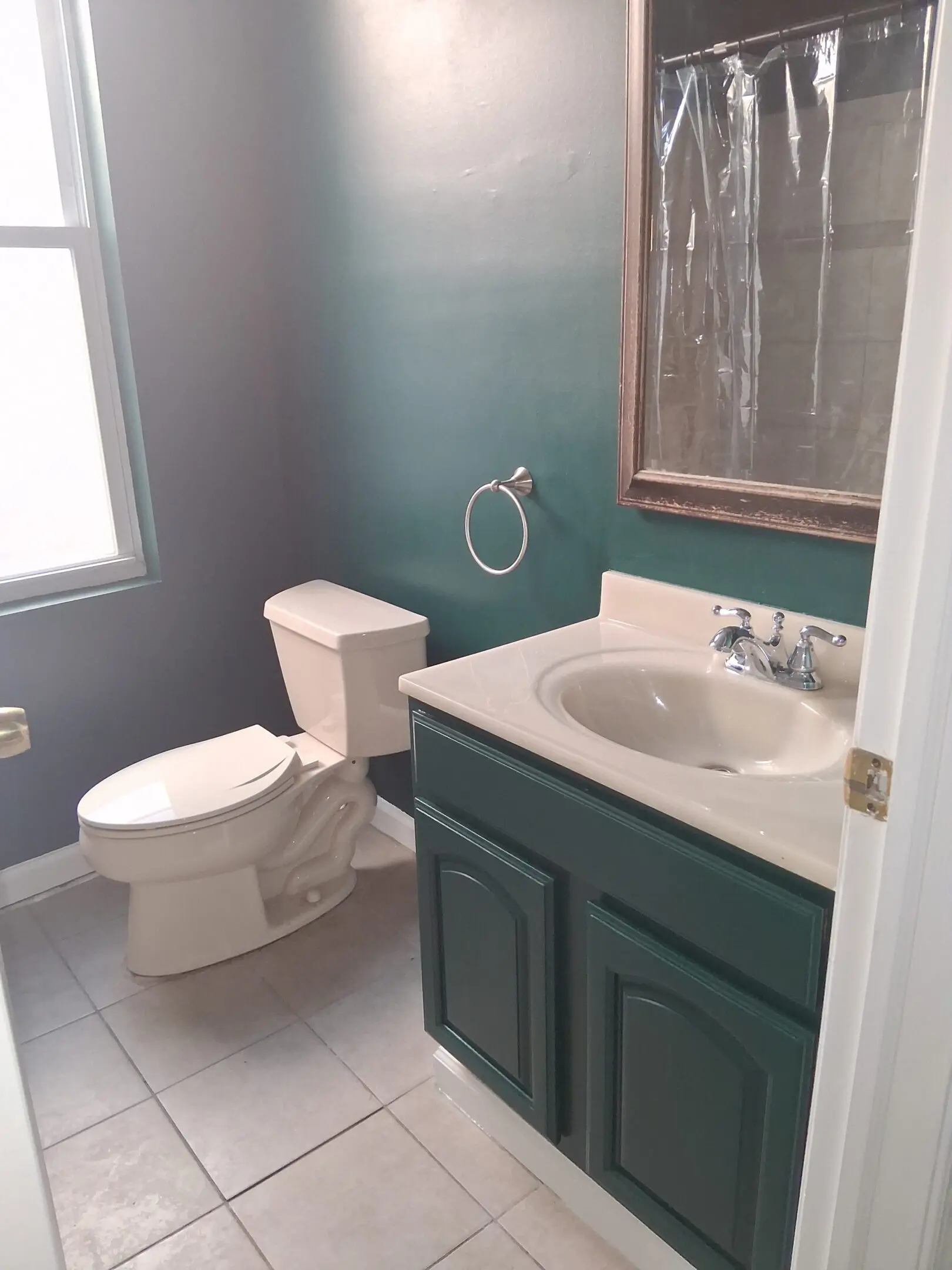 Small bathroom with teal walls, white fixtures, and a window.