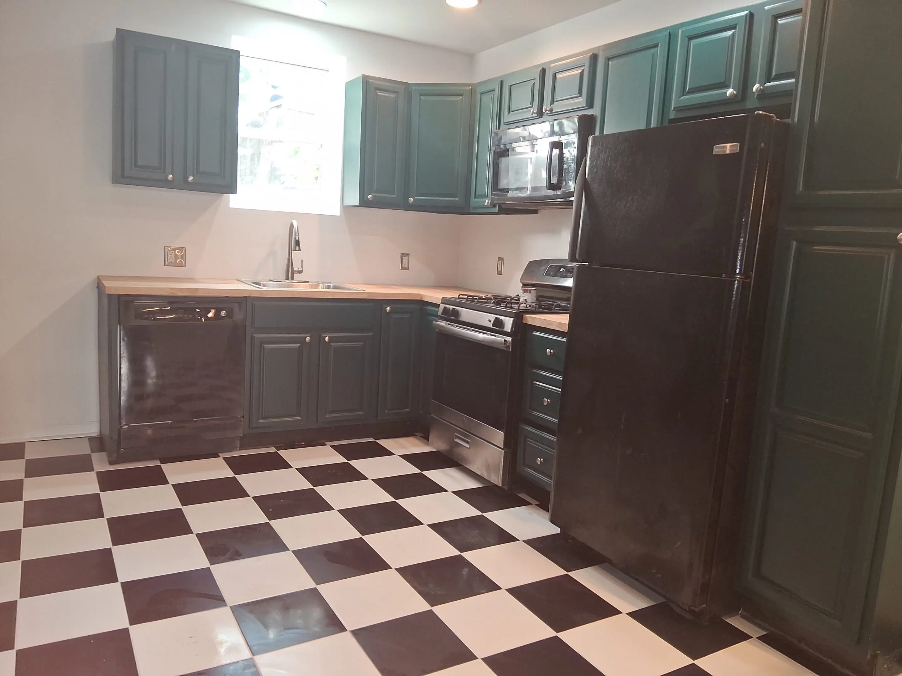 Kitchen with black and white checkered floor and dark cabinetry.