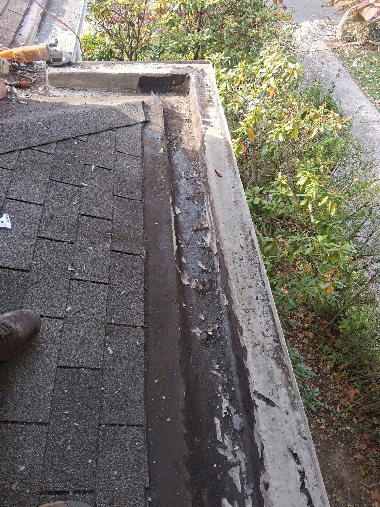 A damaged roof edge with missing shingles and exposed wood.