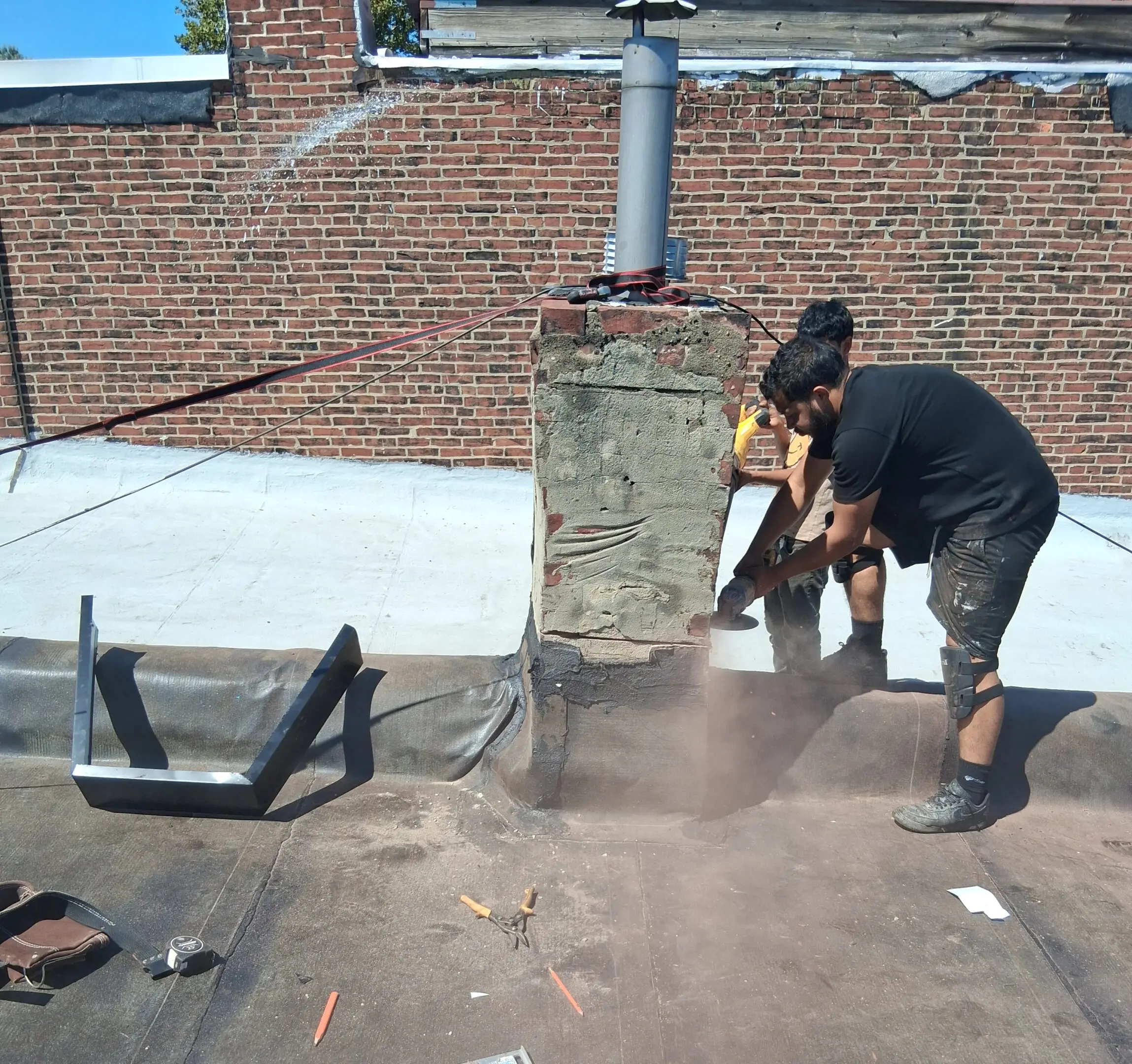 A person using a tool to break concrete on a rooftop.