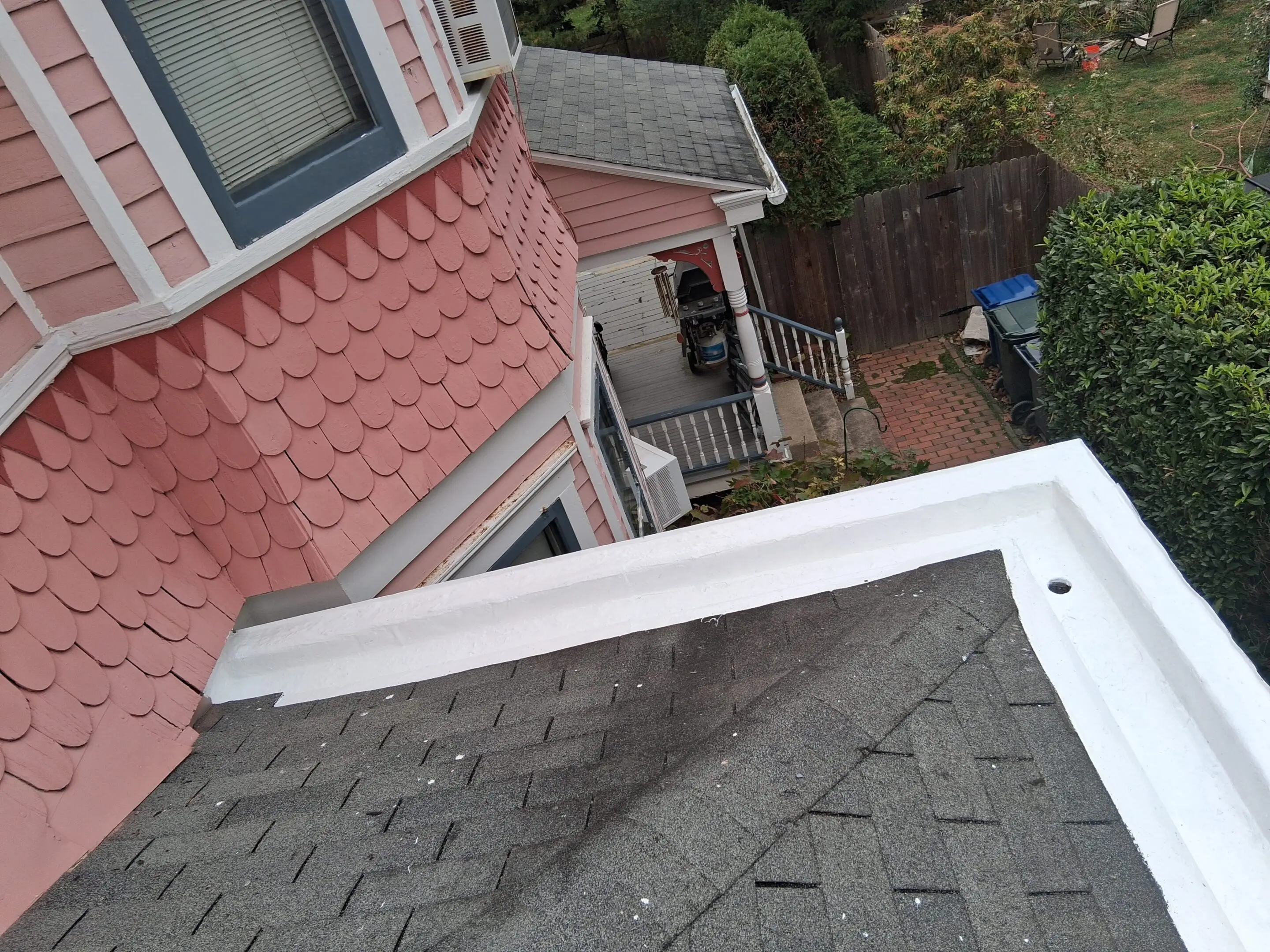 A rooftop with shingles and white guttering on a residential house.