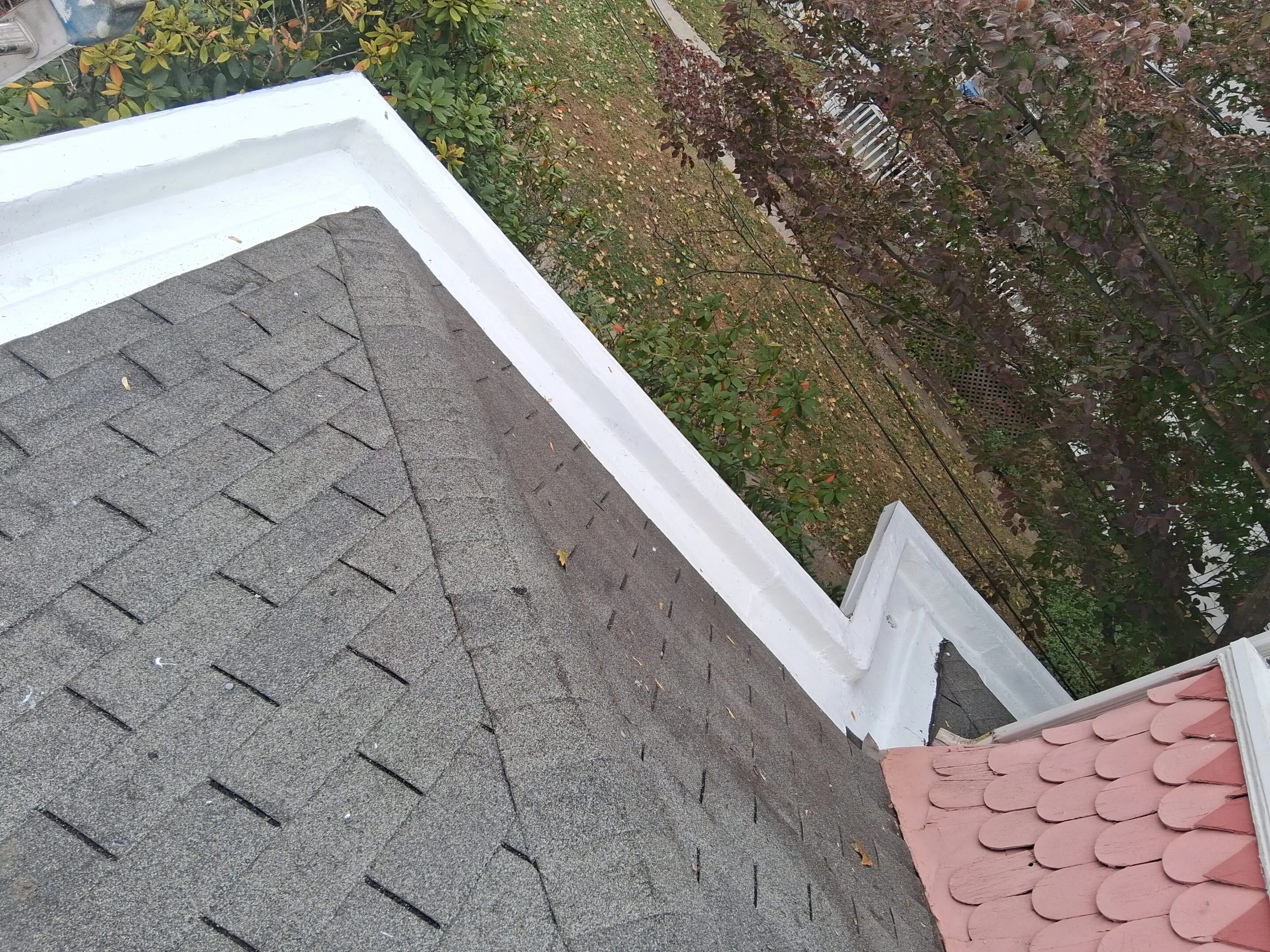 A rooftop with gray shingles and a white gutter.