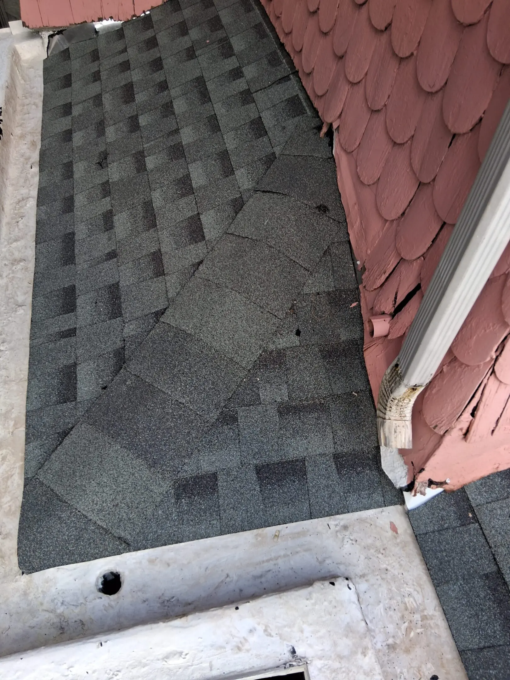 Newly installed asphalt shingles on a roof corner.
