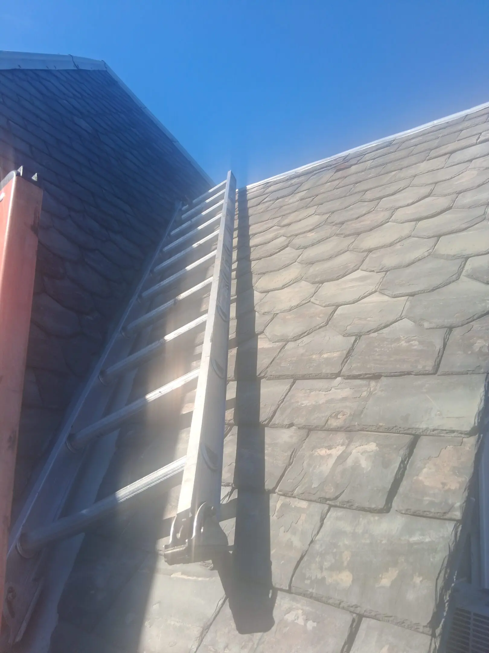Ladder leaning against a roof with hexagonal shingles.