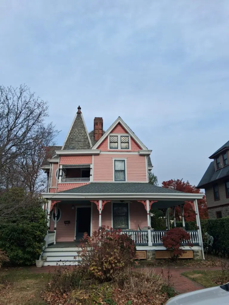 A large, old Victorian house with pink siding and a pointed turret.