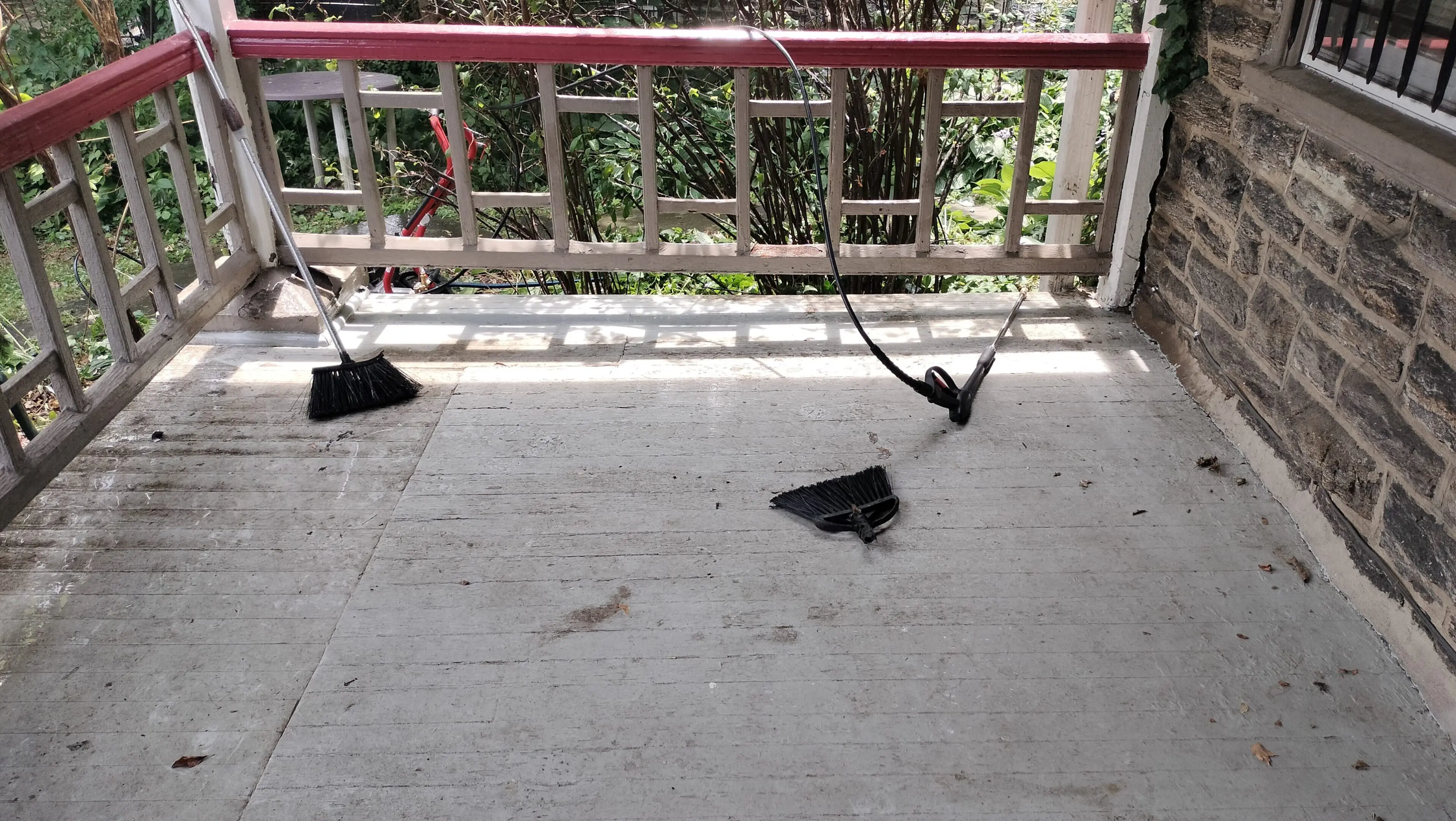A broken chair lies on a balcony floor beside a red railing.