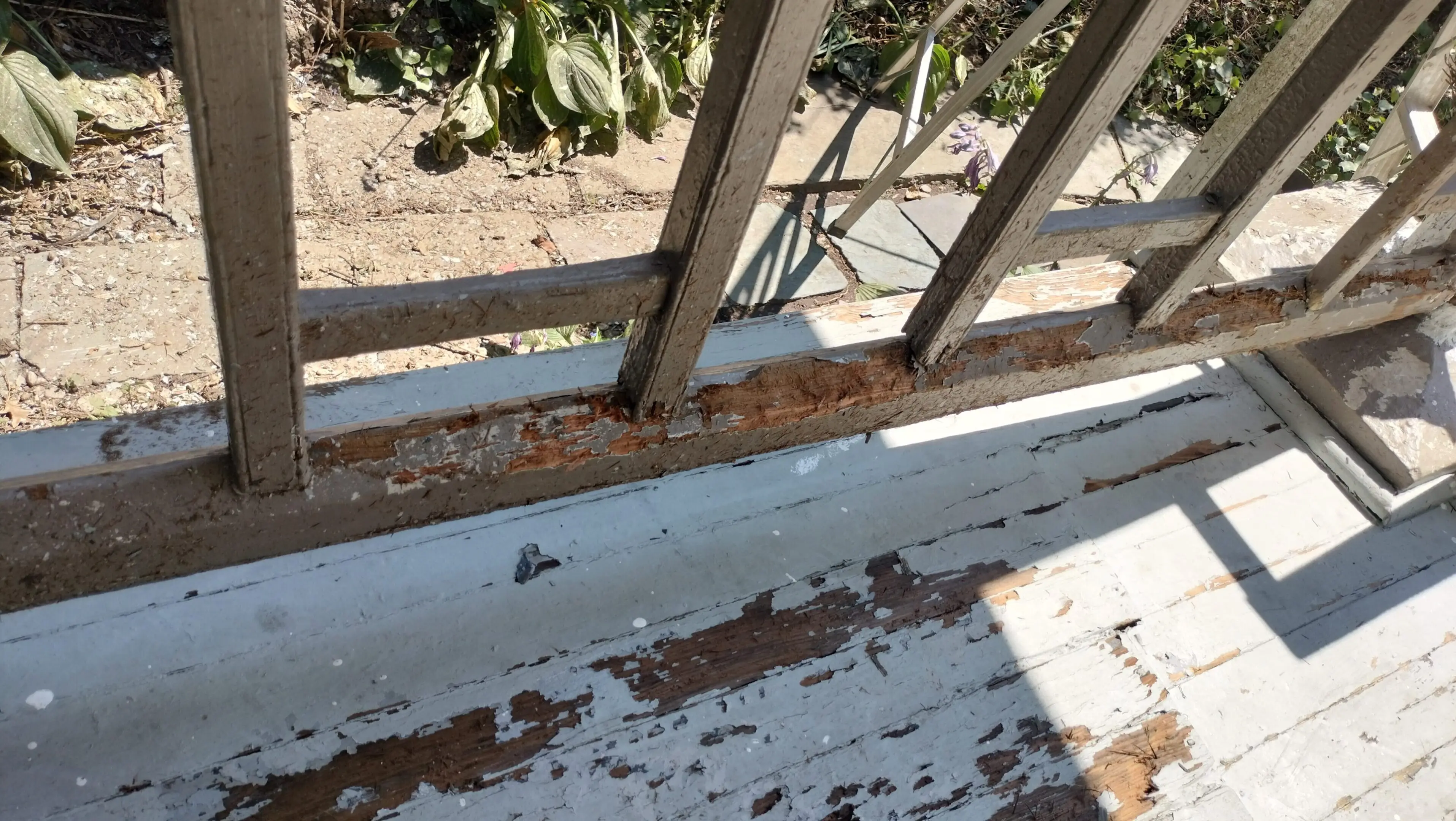 Rust and peeling paint on a metal railing and wooden surface.