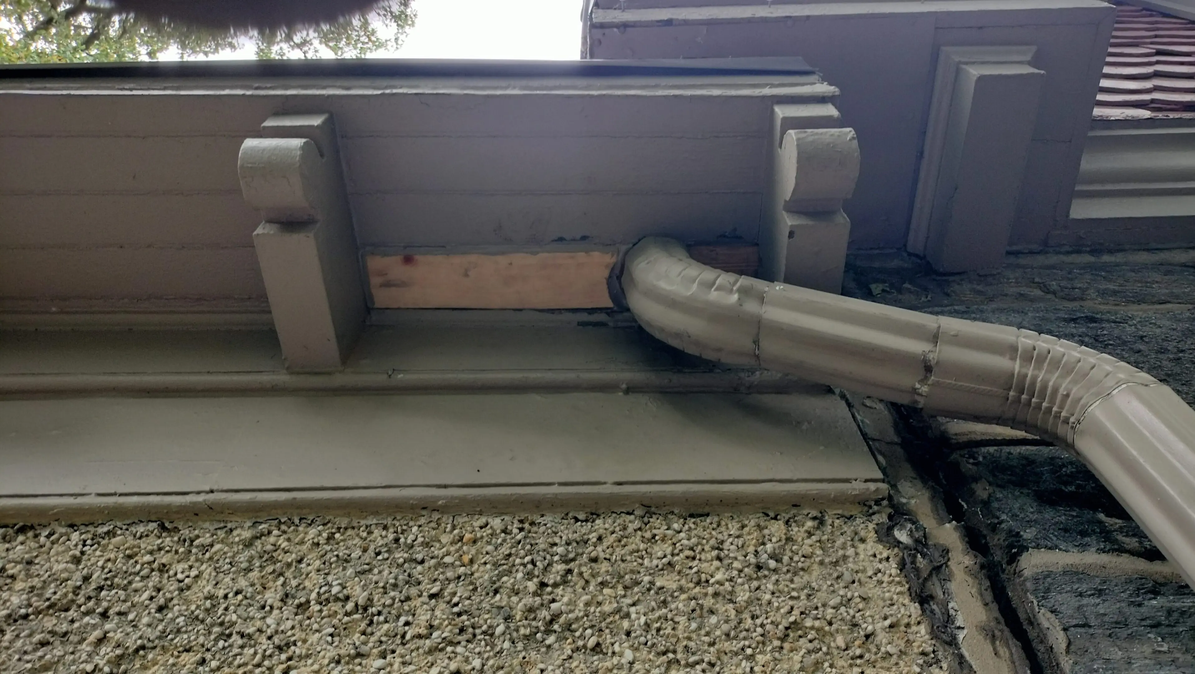 Close-up of a gutter and downspout on a building exterior.