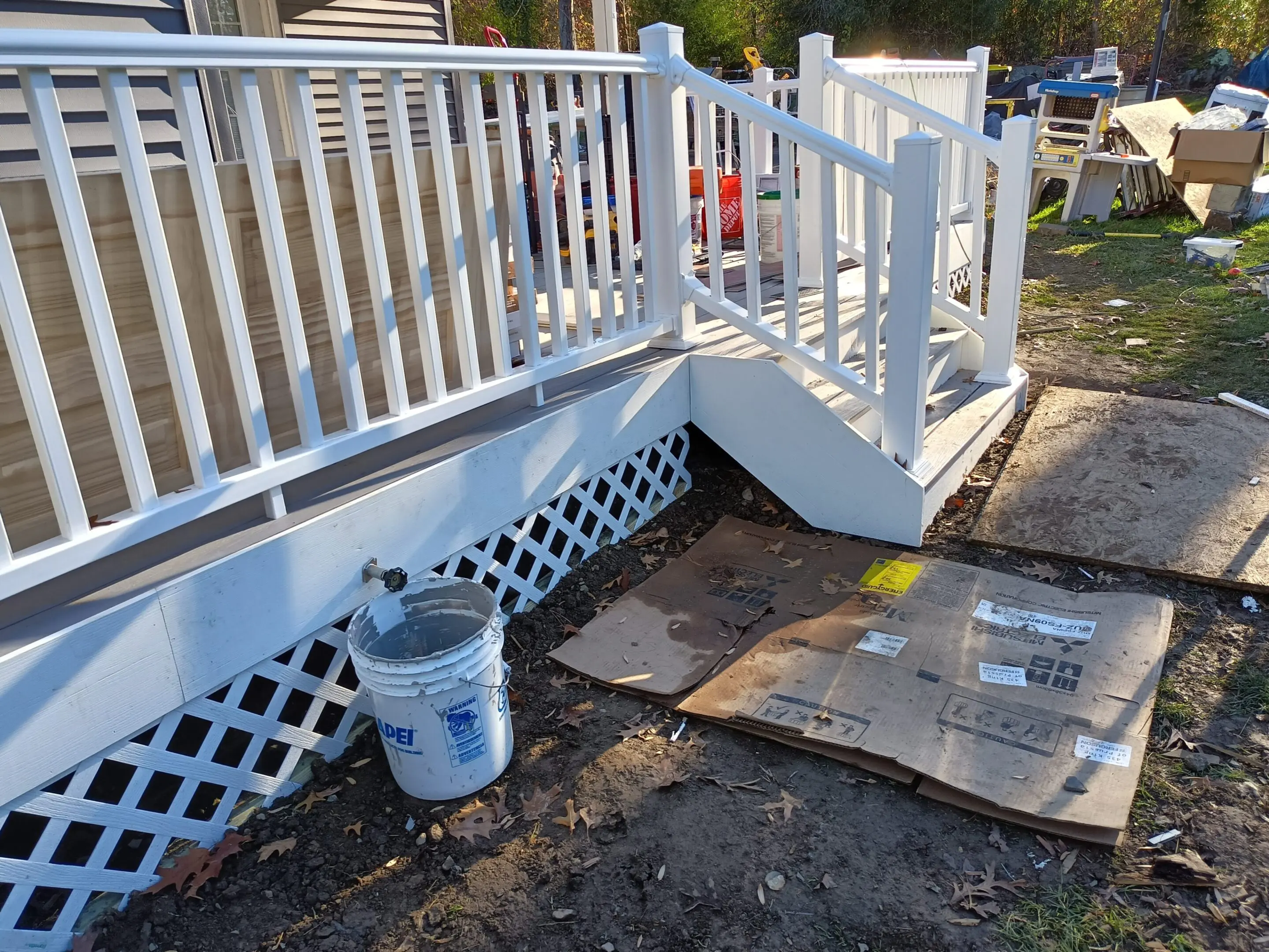 Freshly painted white porch railing and stairs with painting supplies nearby.