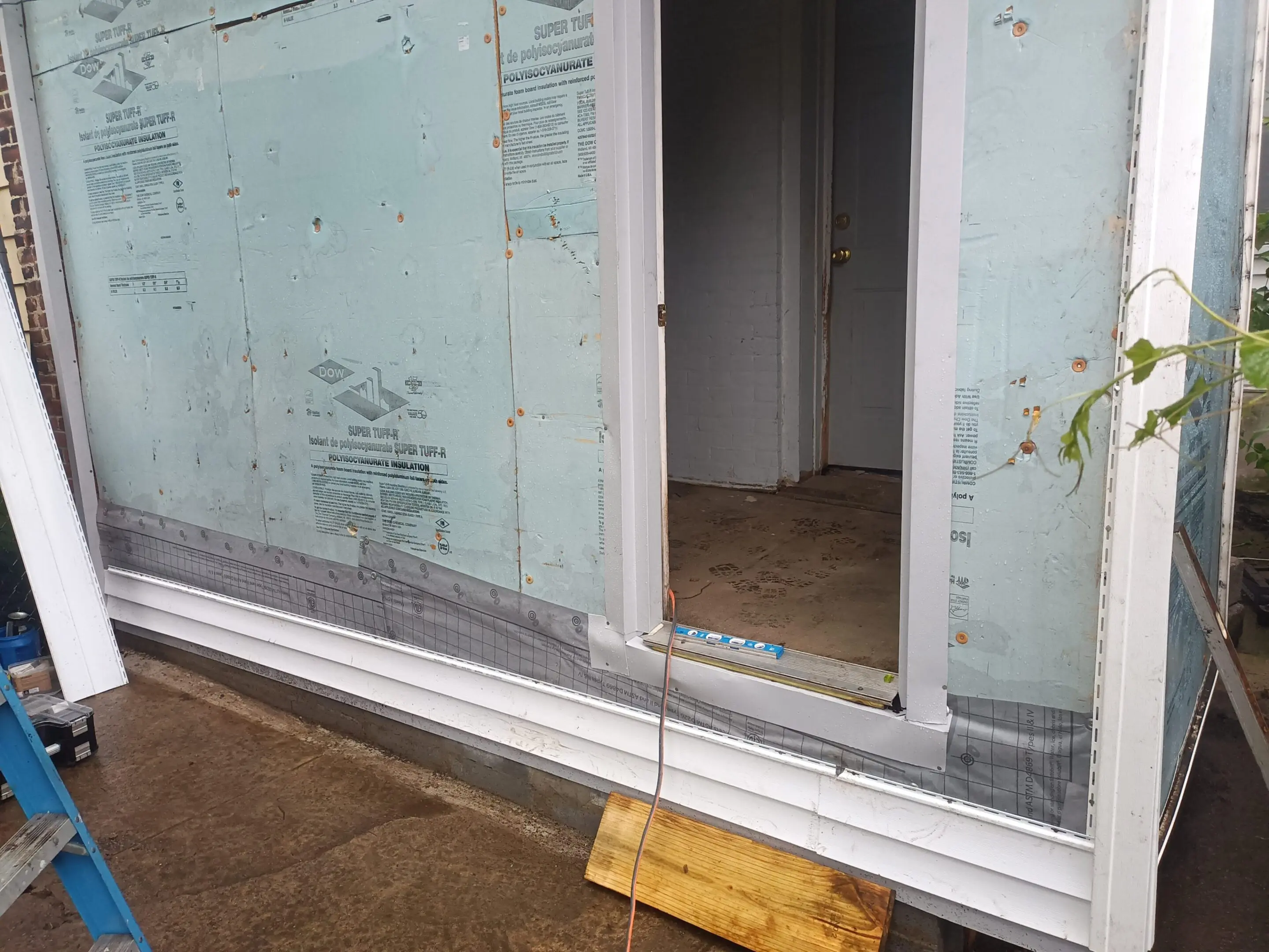 Glass door with a wooden block stopper on a wet floor.