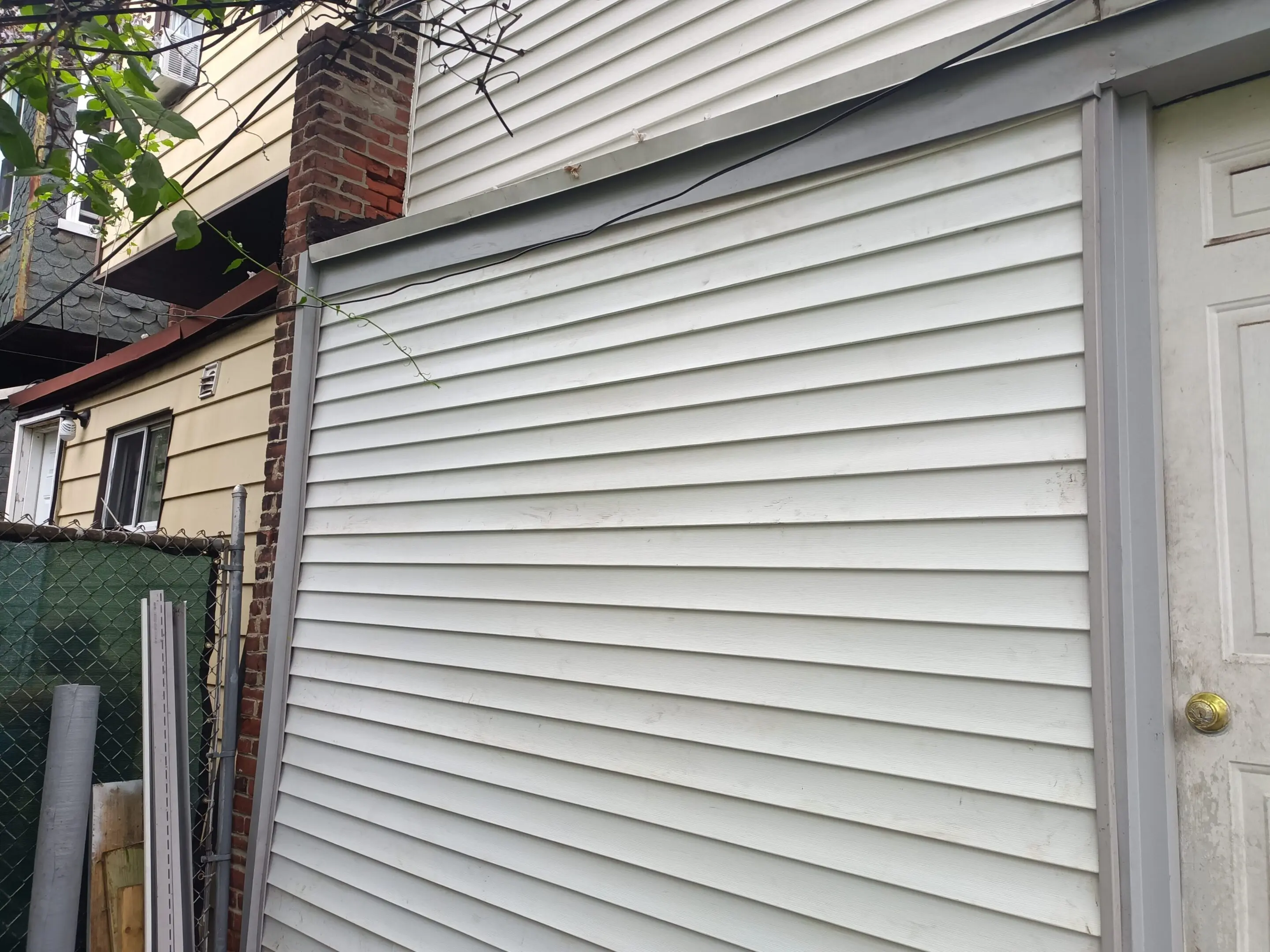 Close-up of white metal siding with horizontal ridges on a building exterior.