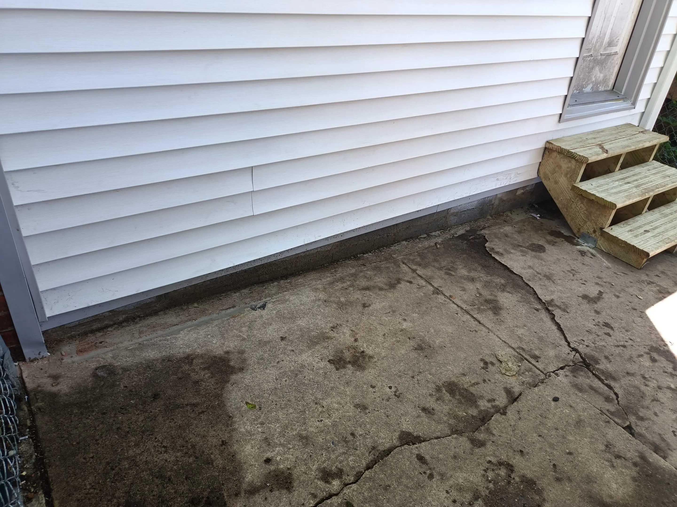 Wet concrete floor near a white wall with water stains.