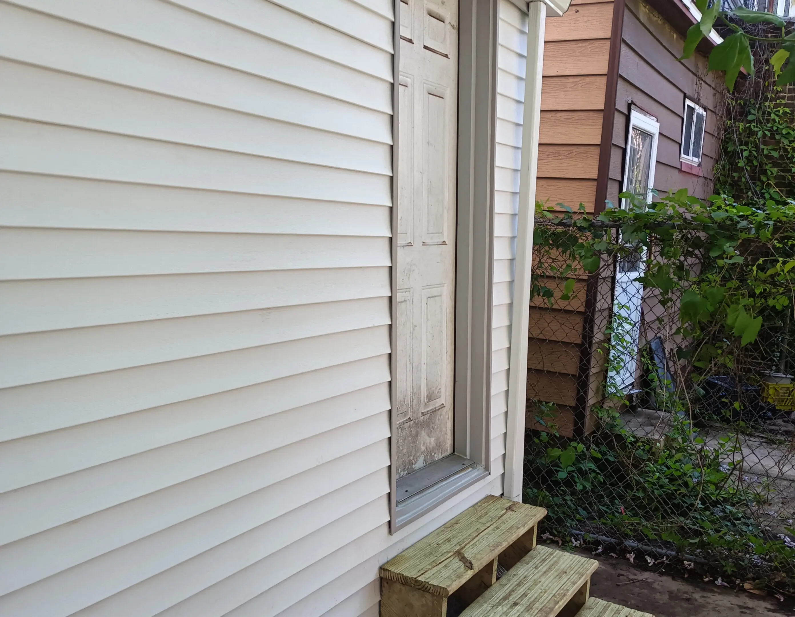 A small wooden staircase leads to a door between two houses.