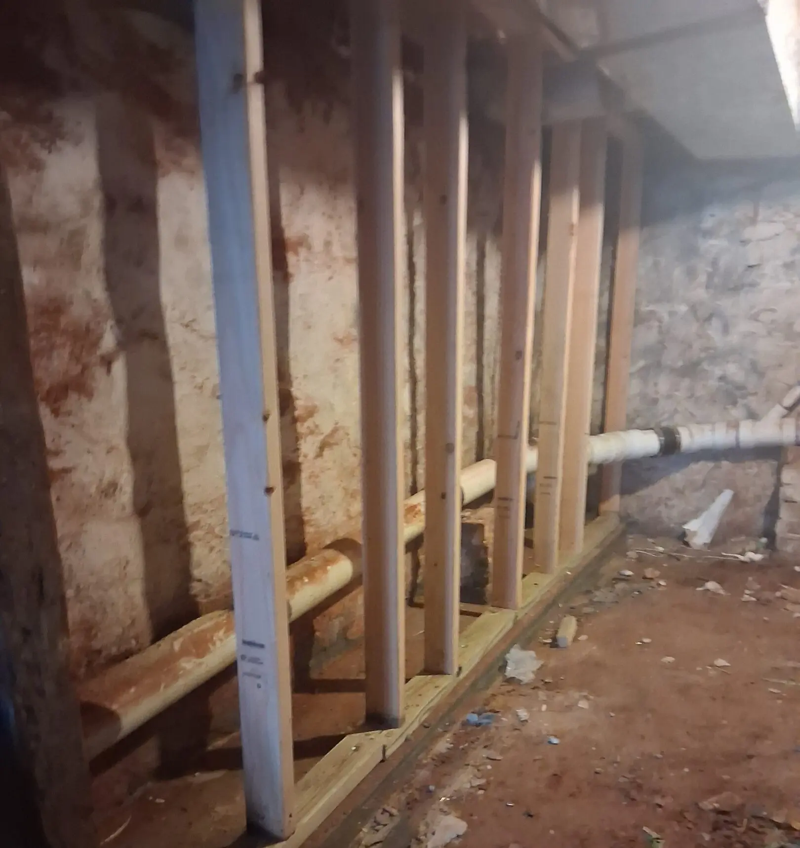 Wooden studs installed in a basement wall for framing.